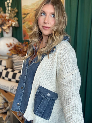 Woman wearing a cream open-knit twofer sweater with a washed-denim button front, flap pockets, and plaid collar accent.