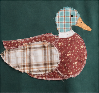 Woman wearing green Mallard Duck Patchwork Knit Top with plaid and floral duck appliqué.