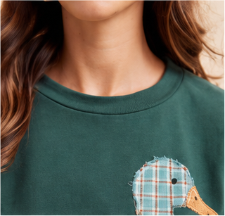 Woman wearing green Mallard Duck Patchwork Knit Top with plaid and floral duck appliqué.