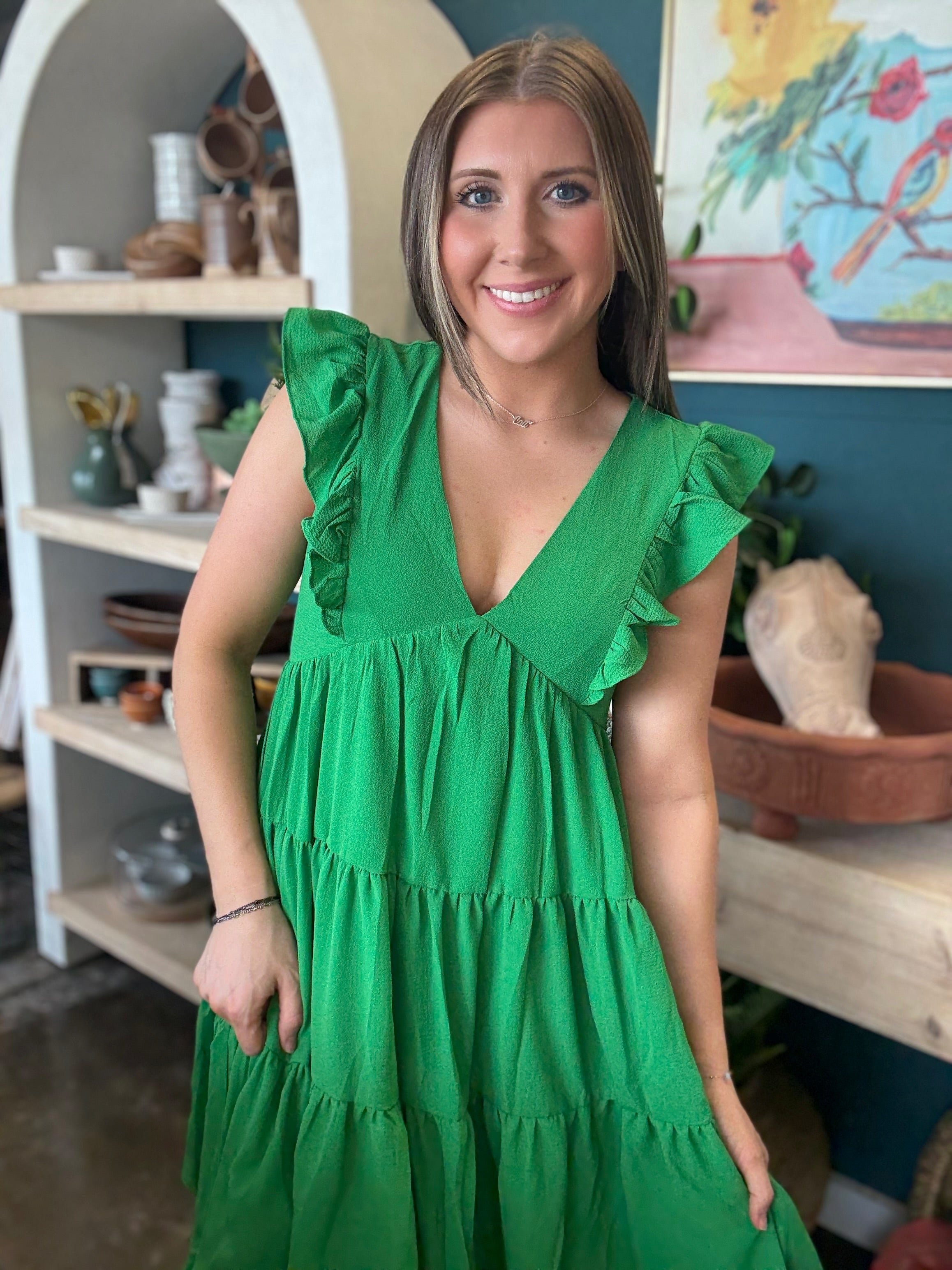 woman wearing emerald green ruffle sleeve tiered boutique dress
