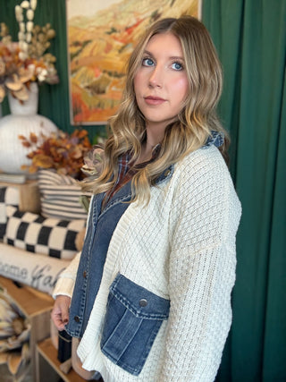 Woman wearing a cream open-knit twofer sweater with a washed-denim button front, flap pockets, and plaid collar accent.