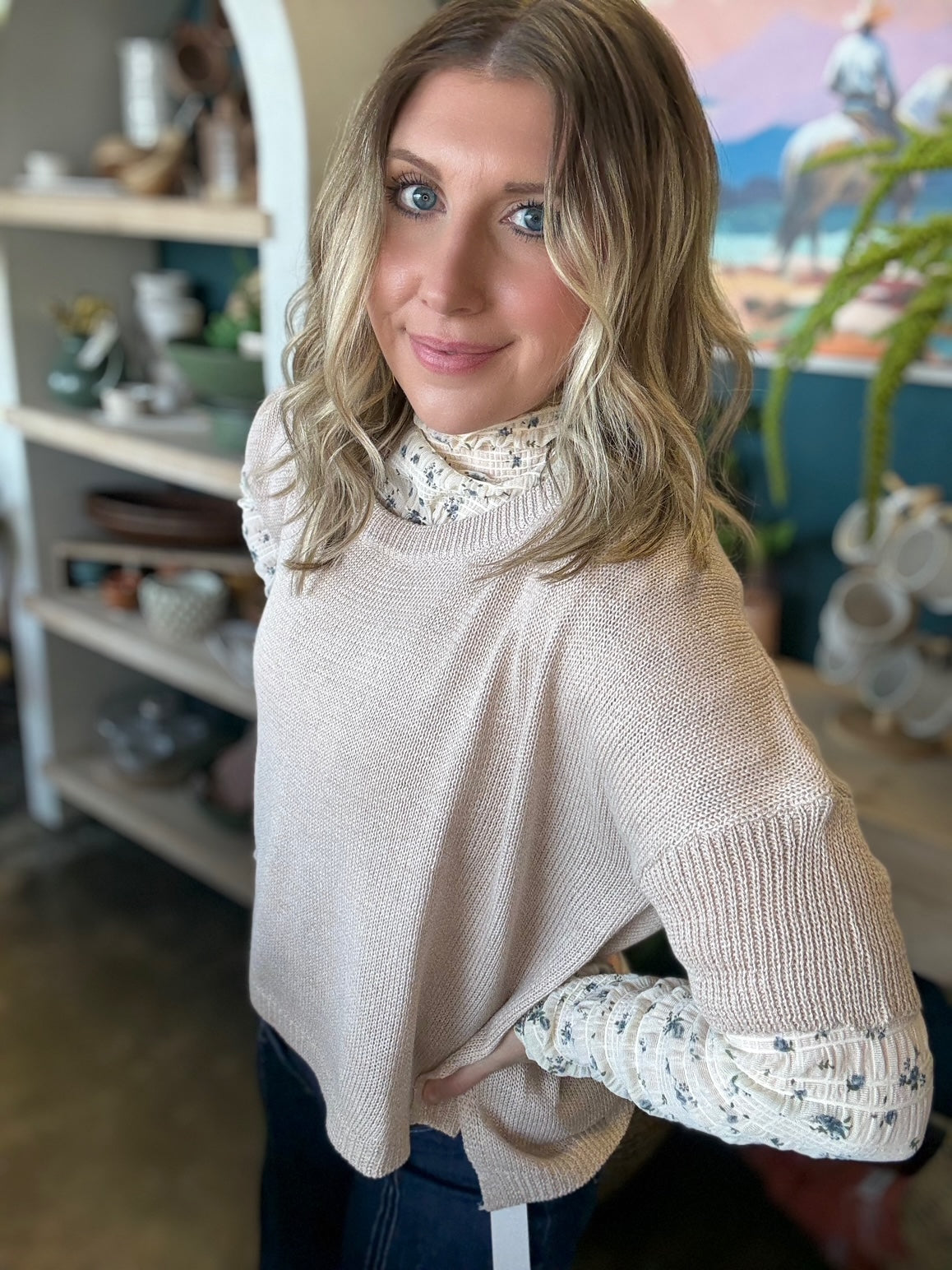 woman wearing oatmeal knit sweater layered over floral textured long sleeve top