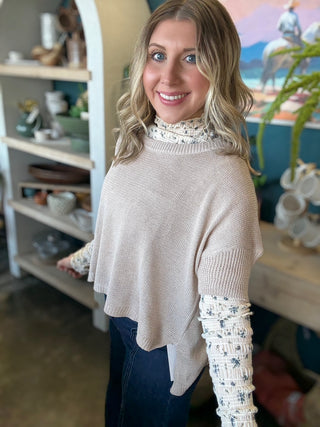 woman wearing oatmeal knit sweater layered over floral textured long sleeve top