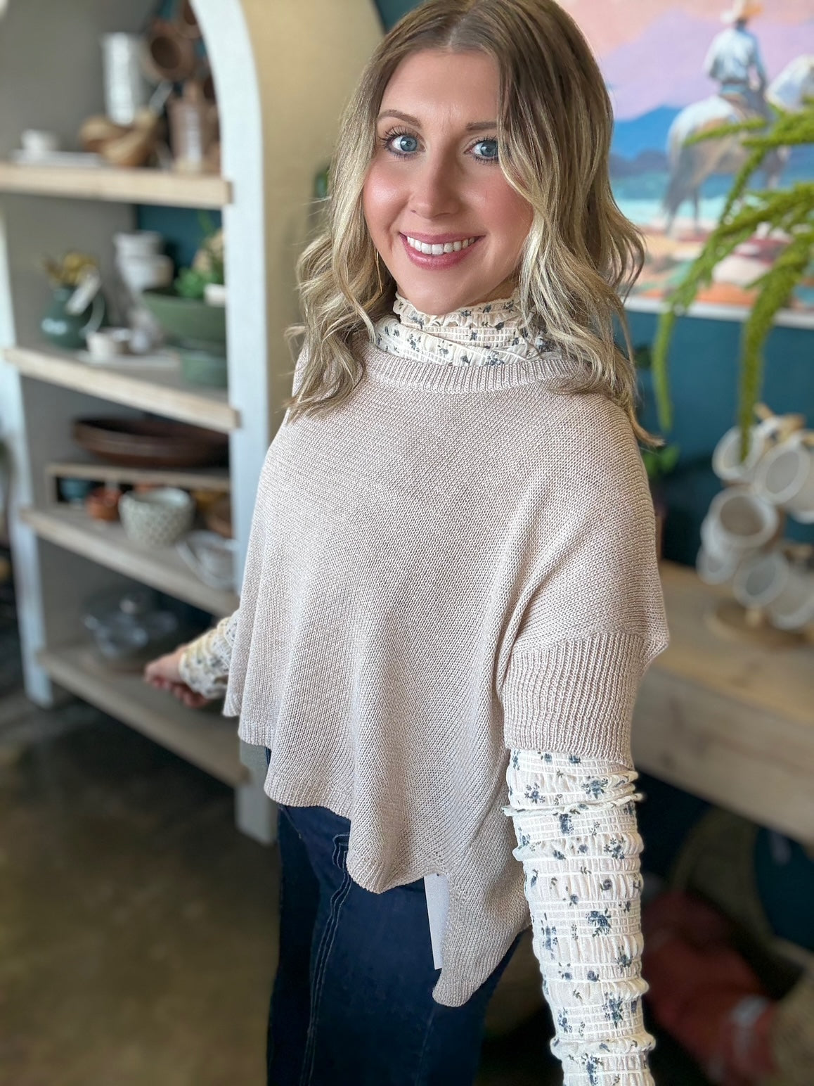 woman wearing oatmeal knit sweater layered over floral textured long sleeve top