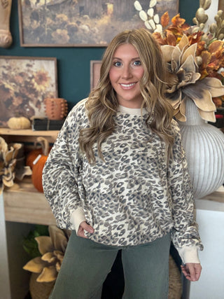 Woman wearing an oatmeal crewneck pullover with gray and taupe leopard print