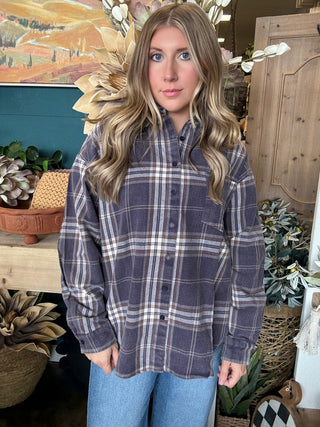 Woman wearing an oversized charcoal, taupe, cream, and brown plaid button-down shirt