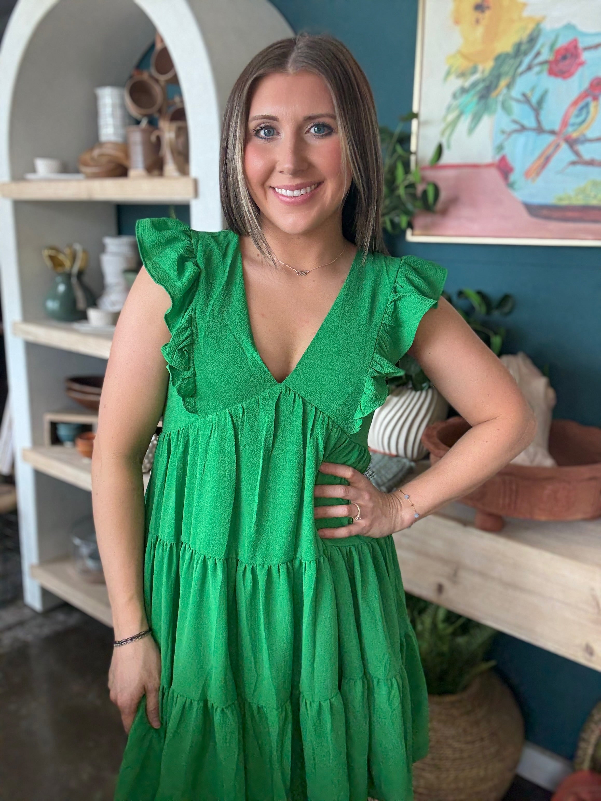 woman wearing emerald green ruffle sleeve tiered boutique dress