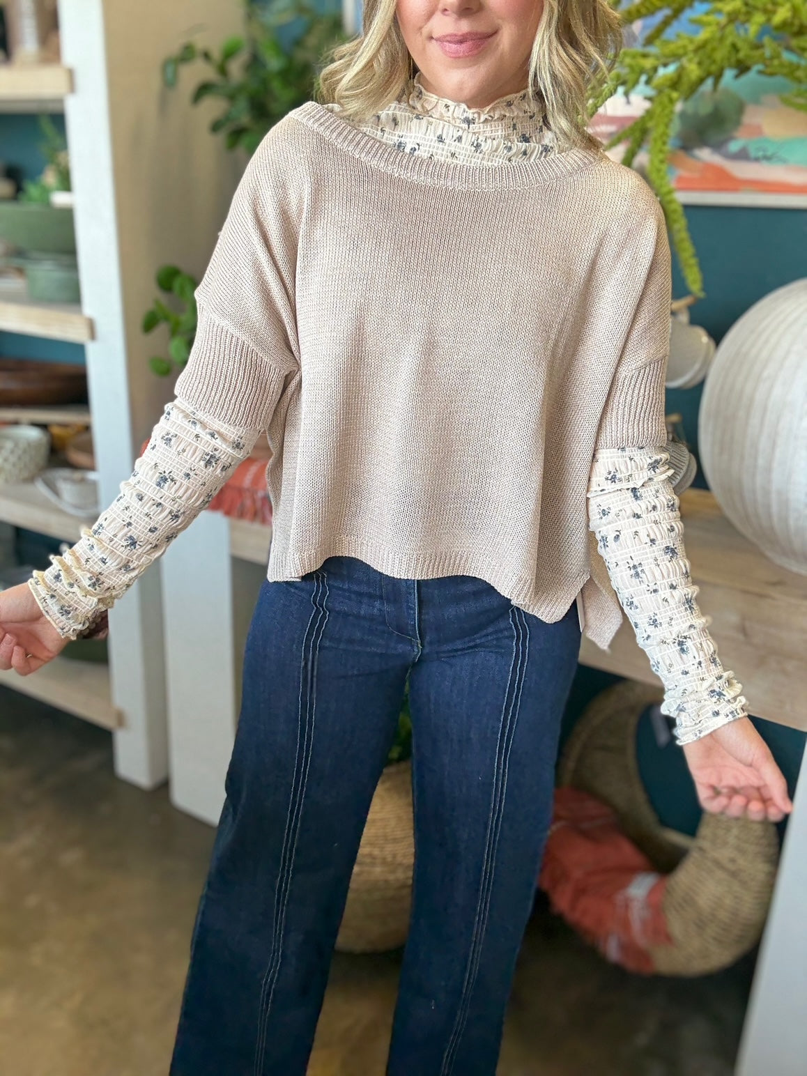woman wearing oatmeal knit sweater layered over floral textured long sleeve top