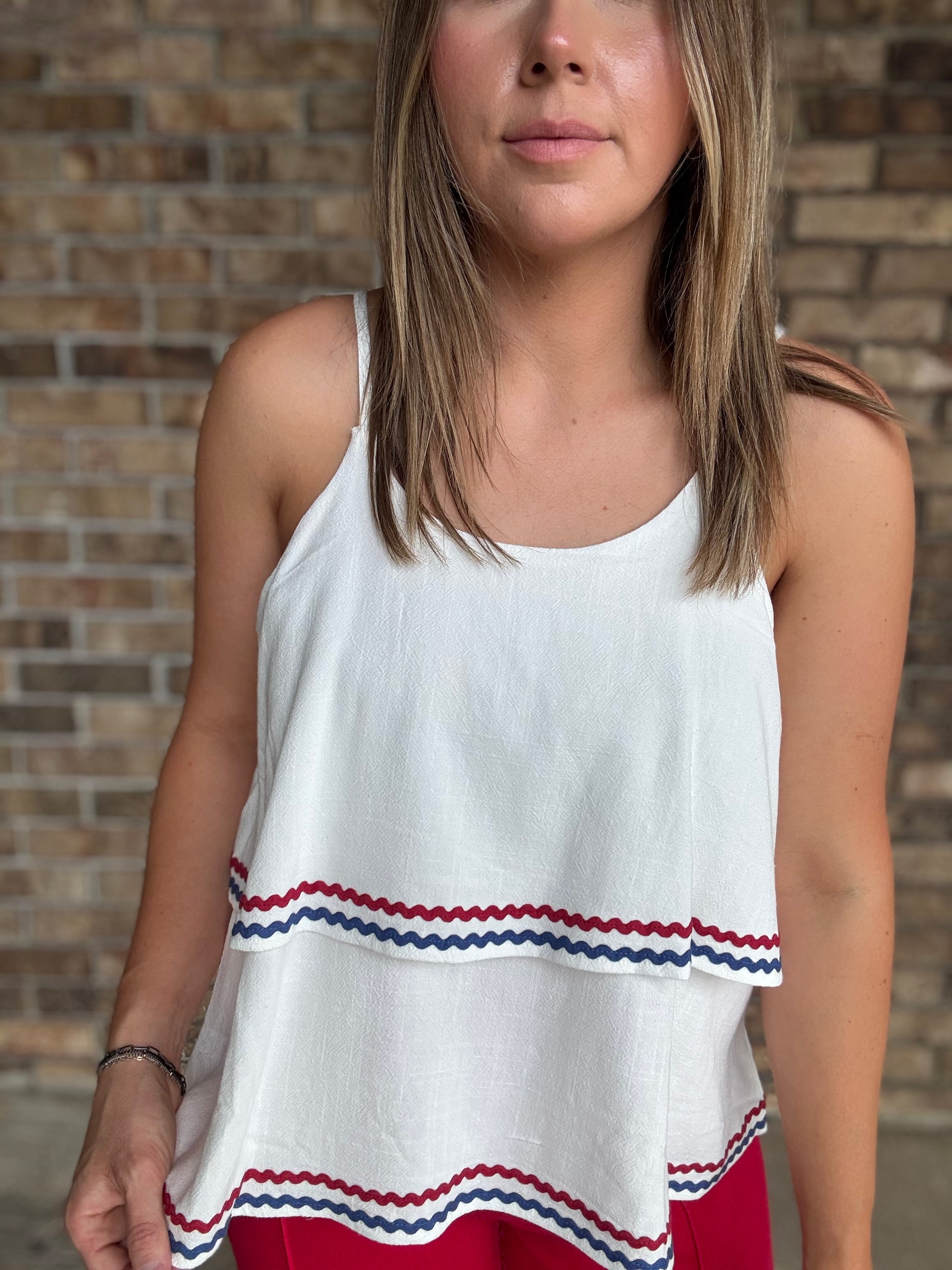 Woman wearing a white double layered woven linen cami top with red and navy ric rac trim