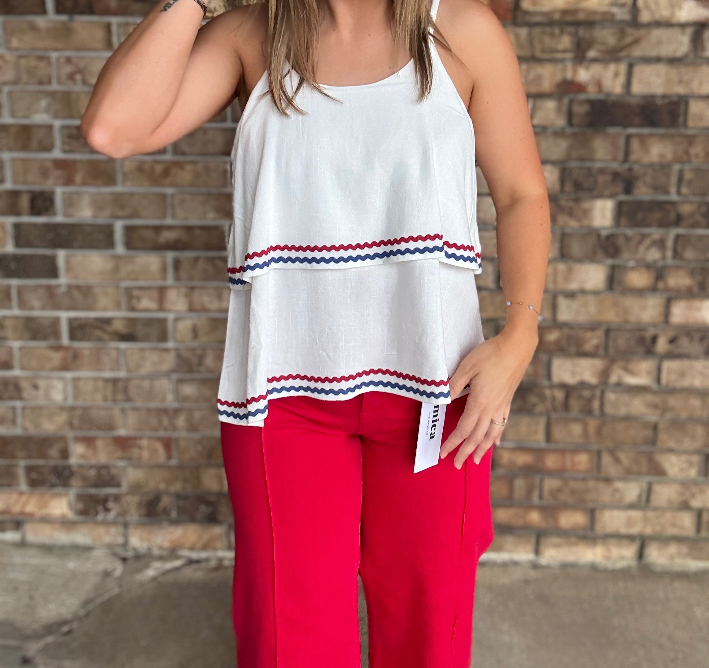 Woman wearing a white double layered woven linen cami top with red and navy ric rac trim