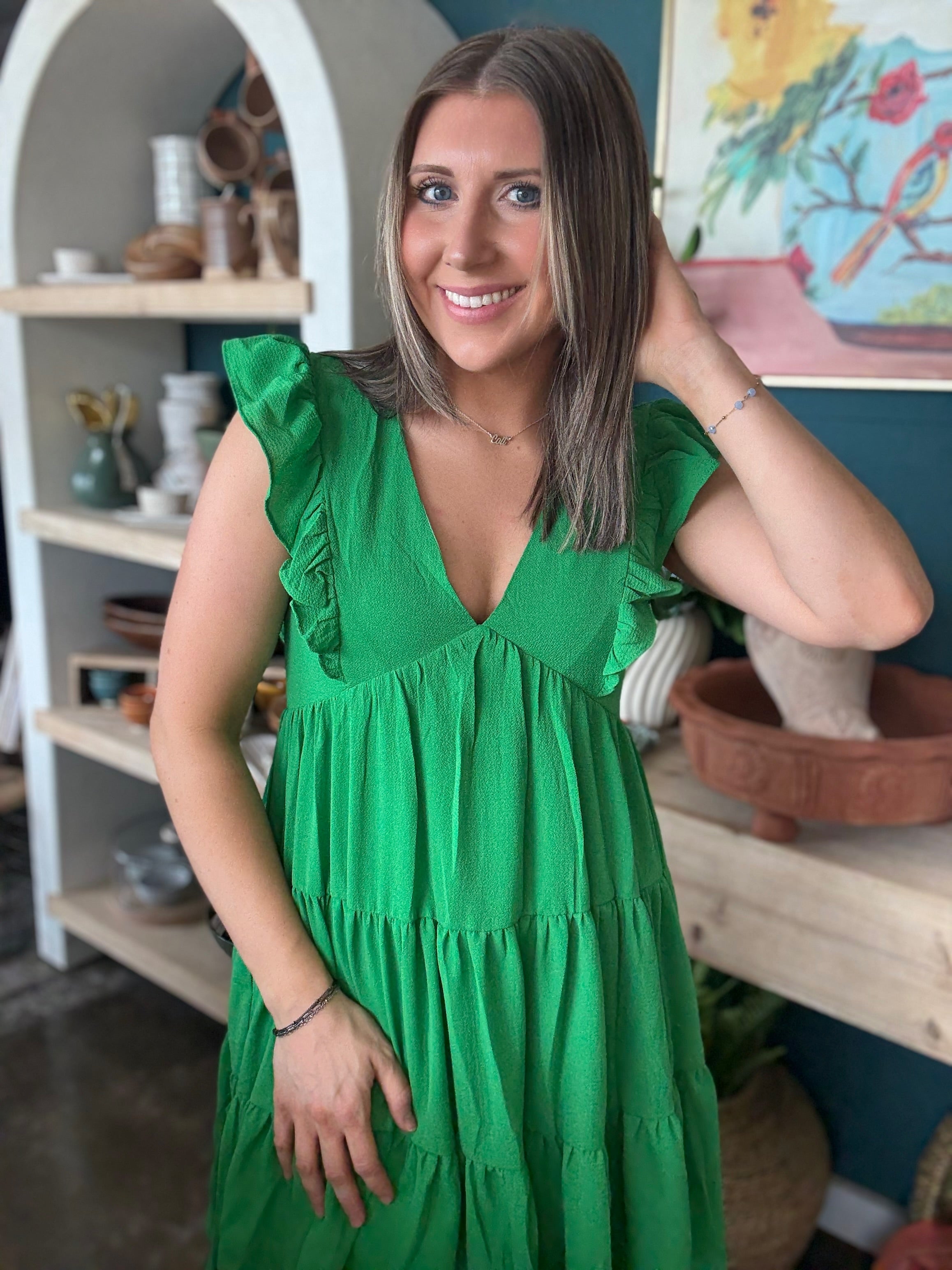 woman wearing emerald green ruffle sleeve tiered boutique dress
