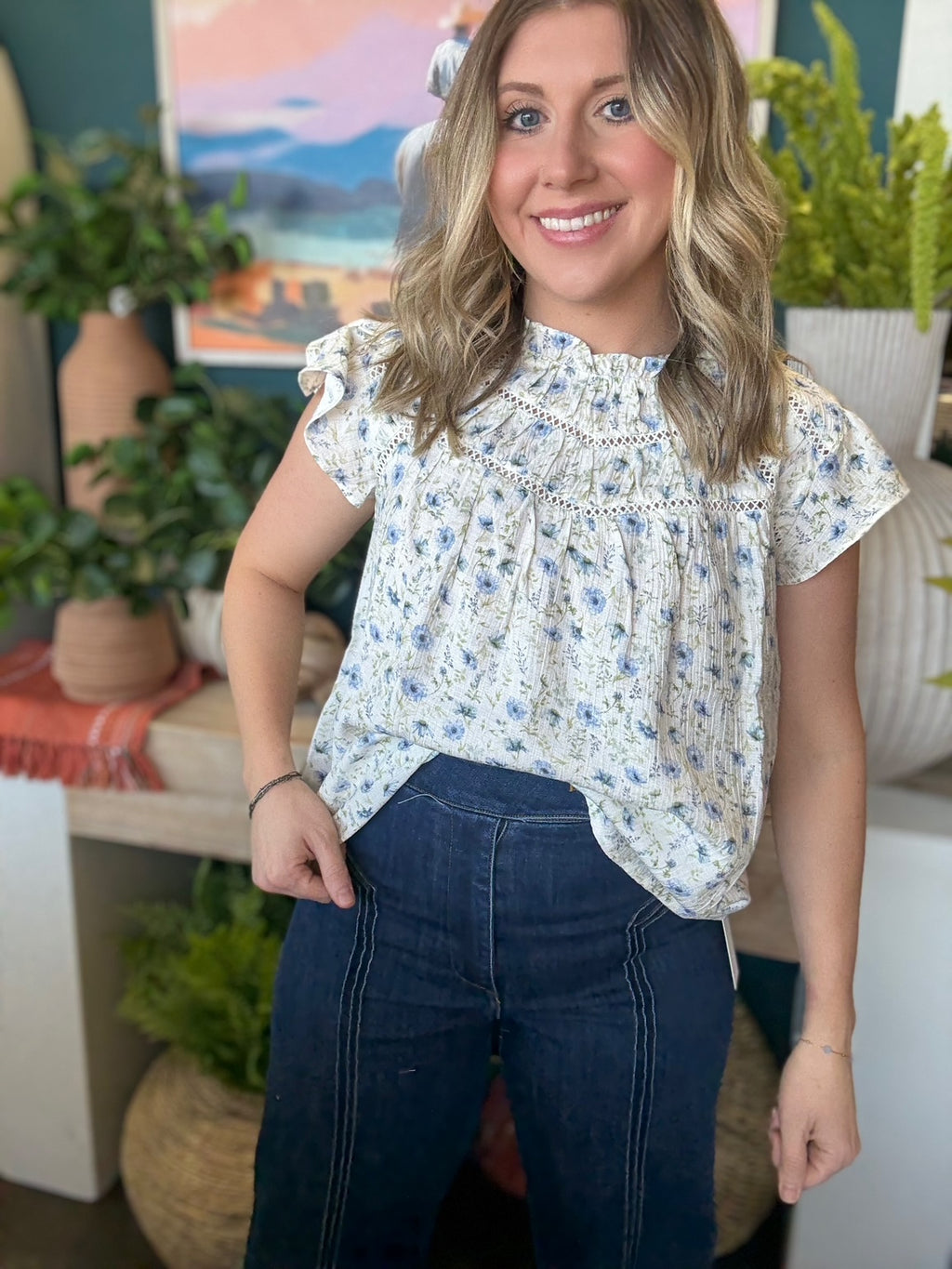 woman wearing cream and blue floral boutique blouse with ruffle neckline