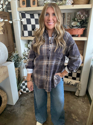 Woman wearing an oversized charcoal, taupe, cream, and brown plaid button-down shirt
