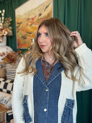 Woman wearing a cream open-knit twofer sweater with a washed-denim button front, flap pockets, and plaid collar accent.