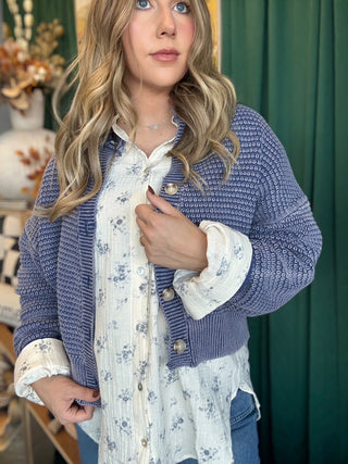 Woman wearing a denim-blue and ivory marled knit button-front cardigan with oversized buttons and dropped shoulders.