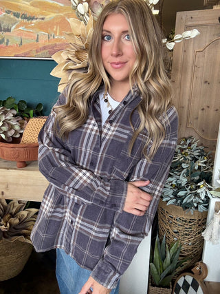 Woman wearing an oversized charcoal, taupe, cream, and brown plaid button-down shirt