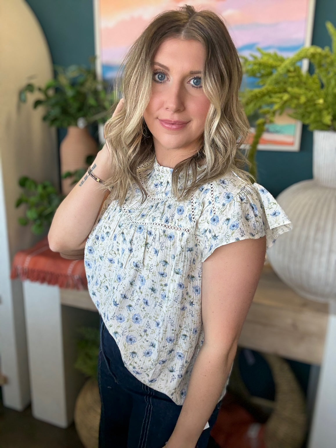 woman wearing cream and blue floral boutique blouse with ruffle neckline