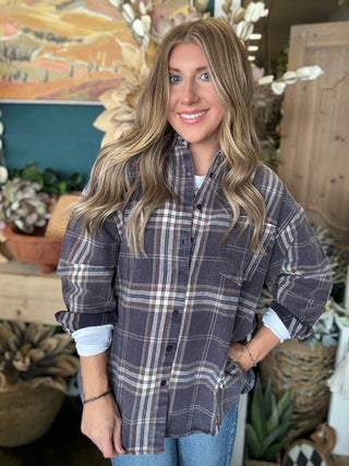 Woman wearing an oversized charcoal, taupe, cream, and brown plaid button-down shirt