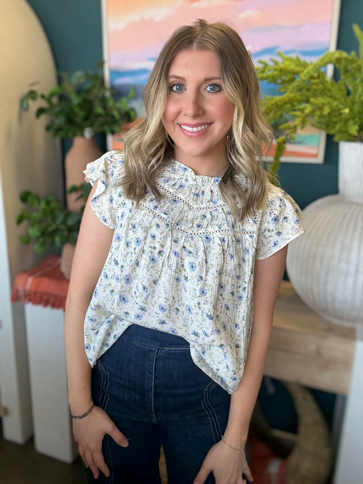 woman wearing cream and blue floral boutique blouse with ruffle neckline