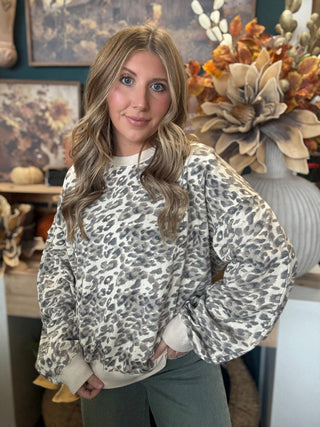 Woman wearing an oatmeal crewneck pullover with gray and taupe leopard print