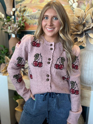 Woman wearing a dusty-pink cherry motif button-front cardigan from Pill Box Boutique
