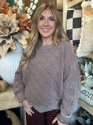 Woman wearing a washed-mocha quilted crew-neck pullover with diamond stitching and exposed seam details