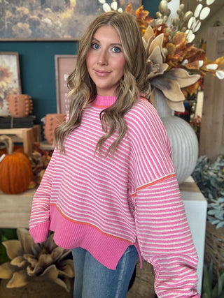Woman wearing a pink-and-cream striped sweater with coral trim
