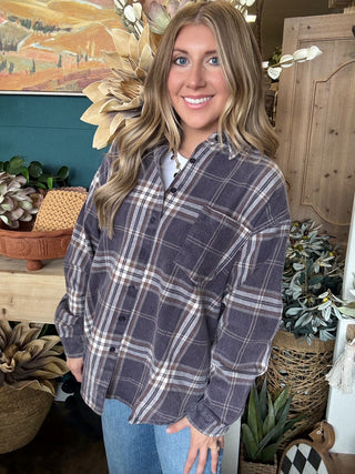 Woman wearing an oversized charcoal, taupe, cream, and brown plaid button-down shirt