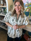 woman wearing ivory and olive printed puff sleeve boutique top with split neckline