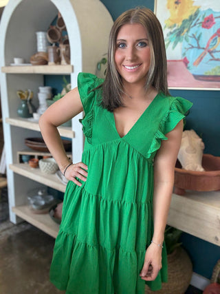 woman wearing emerald green ruffle sleeve tiered boutique dress