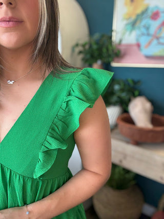 woman wearing emerald green ruffle sleeve tiered boutique dress