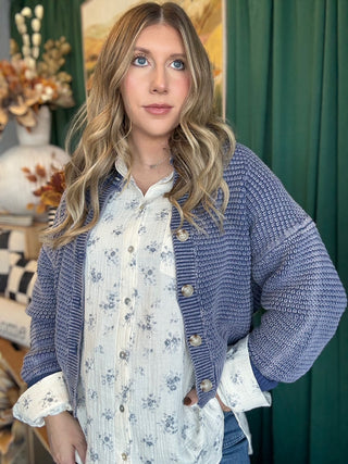 Woman wearing a denim-blue and ivory marled knit button-front cardigan with oversized buttons and dropped shoulders.