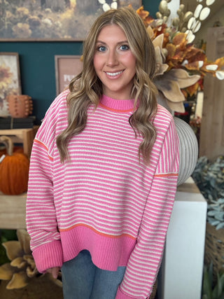 Woman wearing a pink-and-cream striped sweater with coral trim