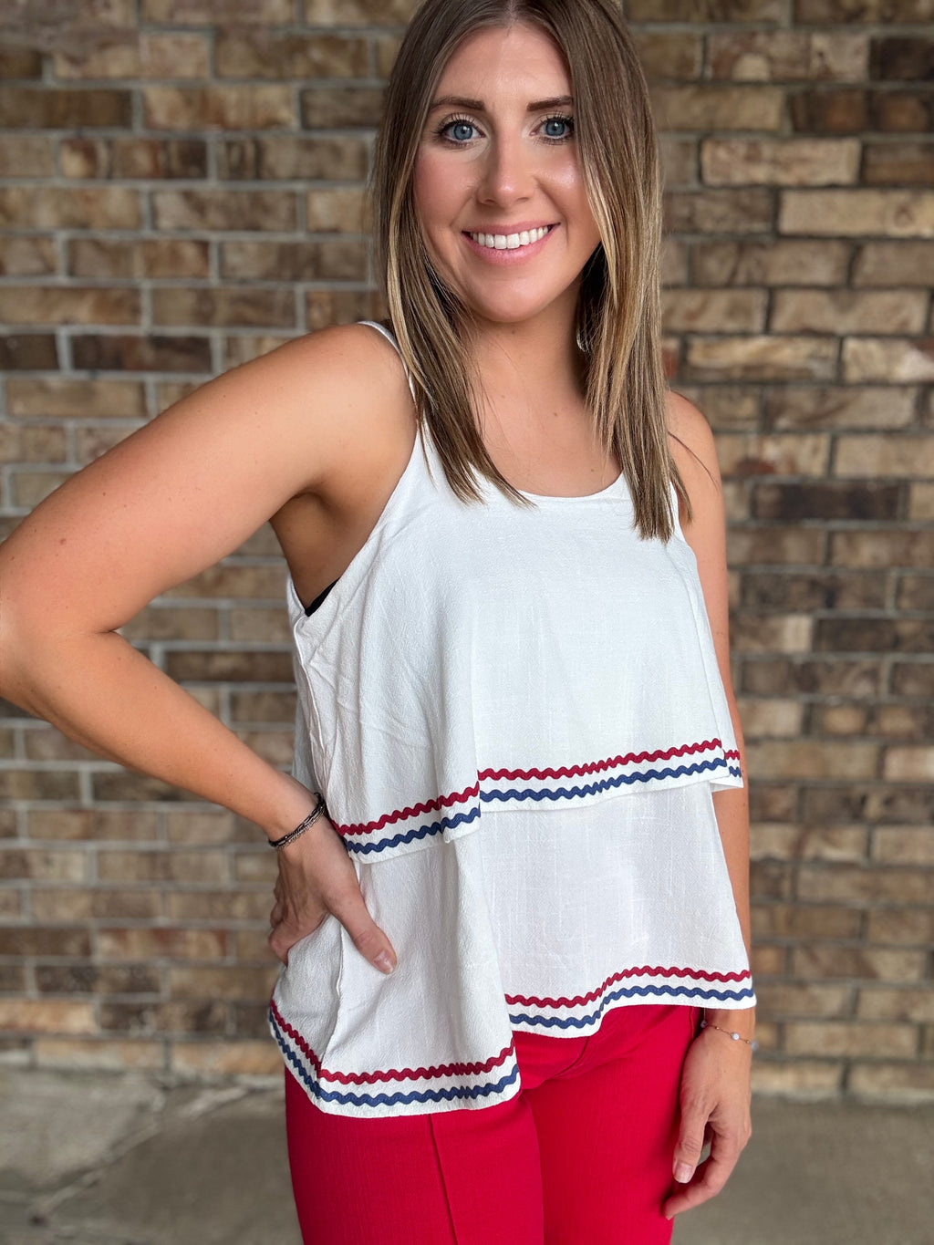 Woman wearing a white double layered woven linen cami top with red and navy ric rac trim