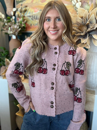 Woman wearing a dusty-pink cherry motif button-front cardigan from Pill Box Boutique