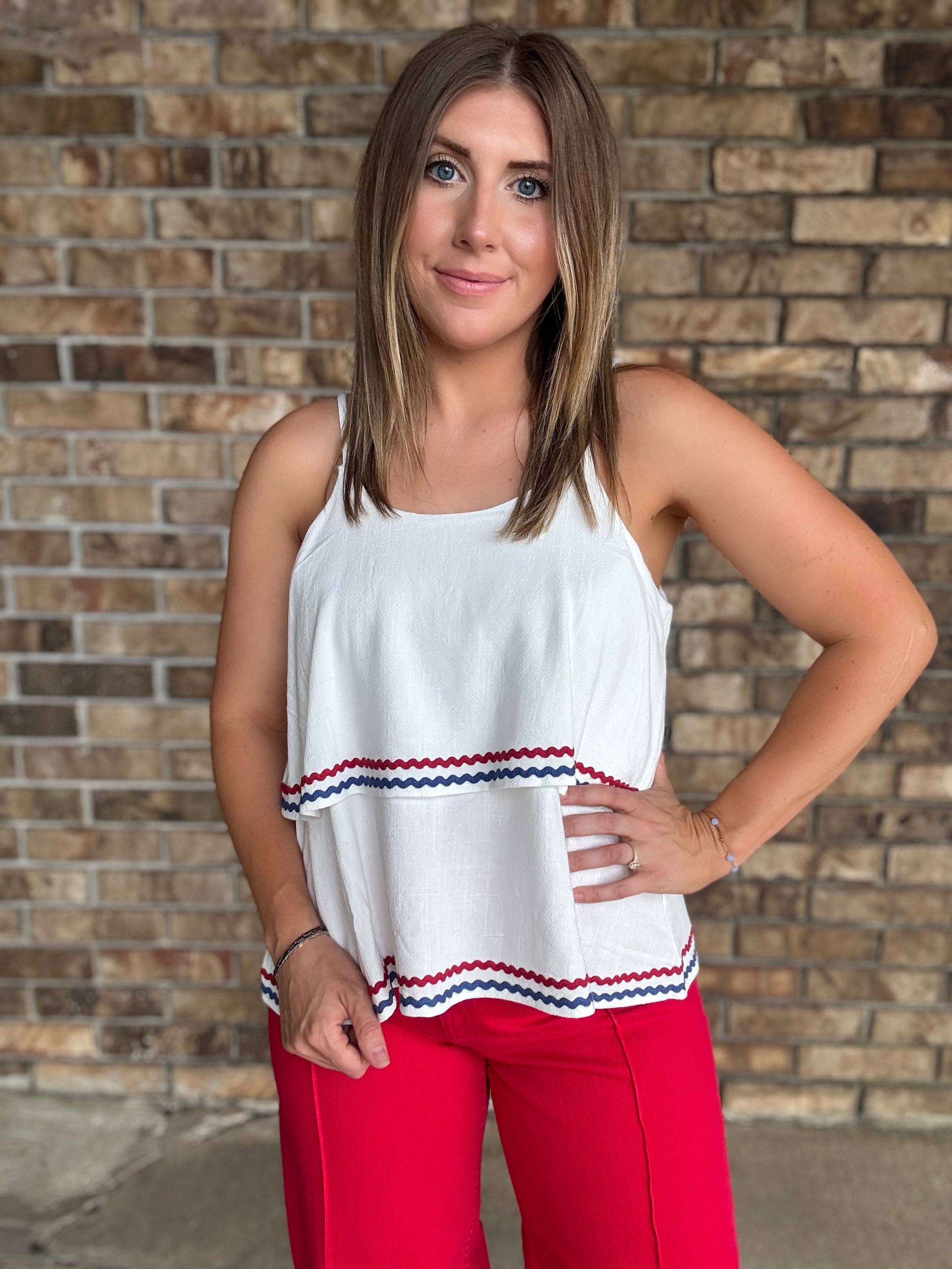 Woman wearing a white double layered woven linen cami top with red and navy ric rac trim