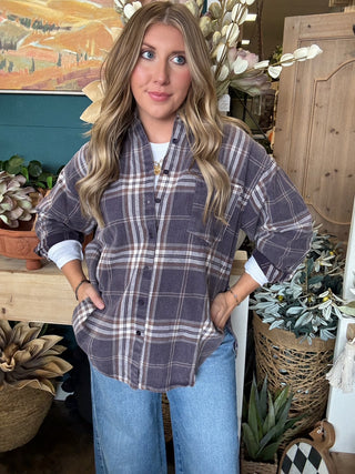 Woman wearing an oversized charcoal, taupe, cream, and brown plaid button-down shirt