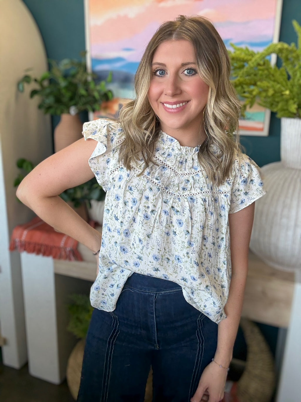woman wearing cream and blue floral boutique blouse with ruffle neckline
