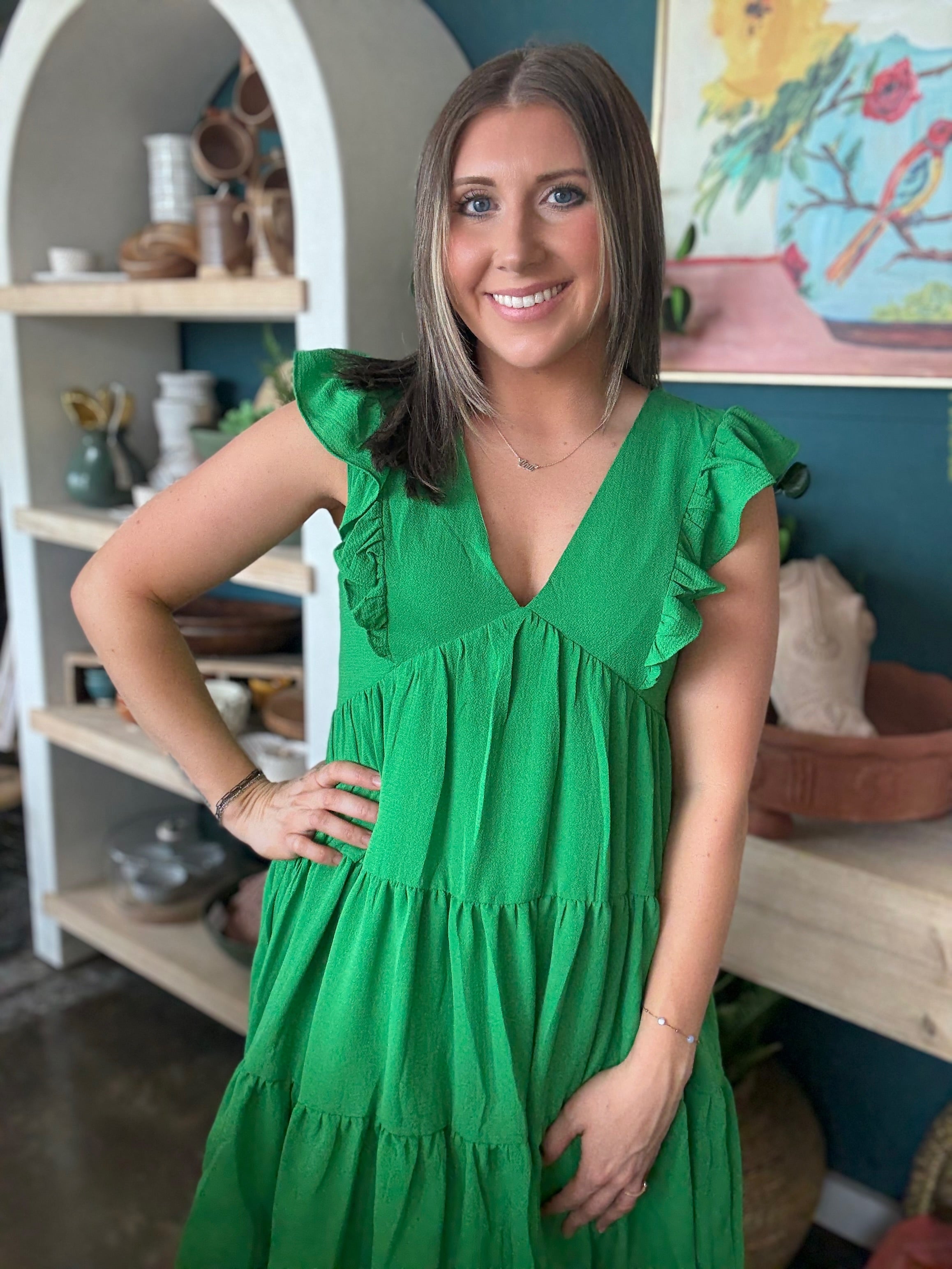 woman wearing emerald green ruffle sleeve tiered boutique dress