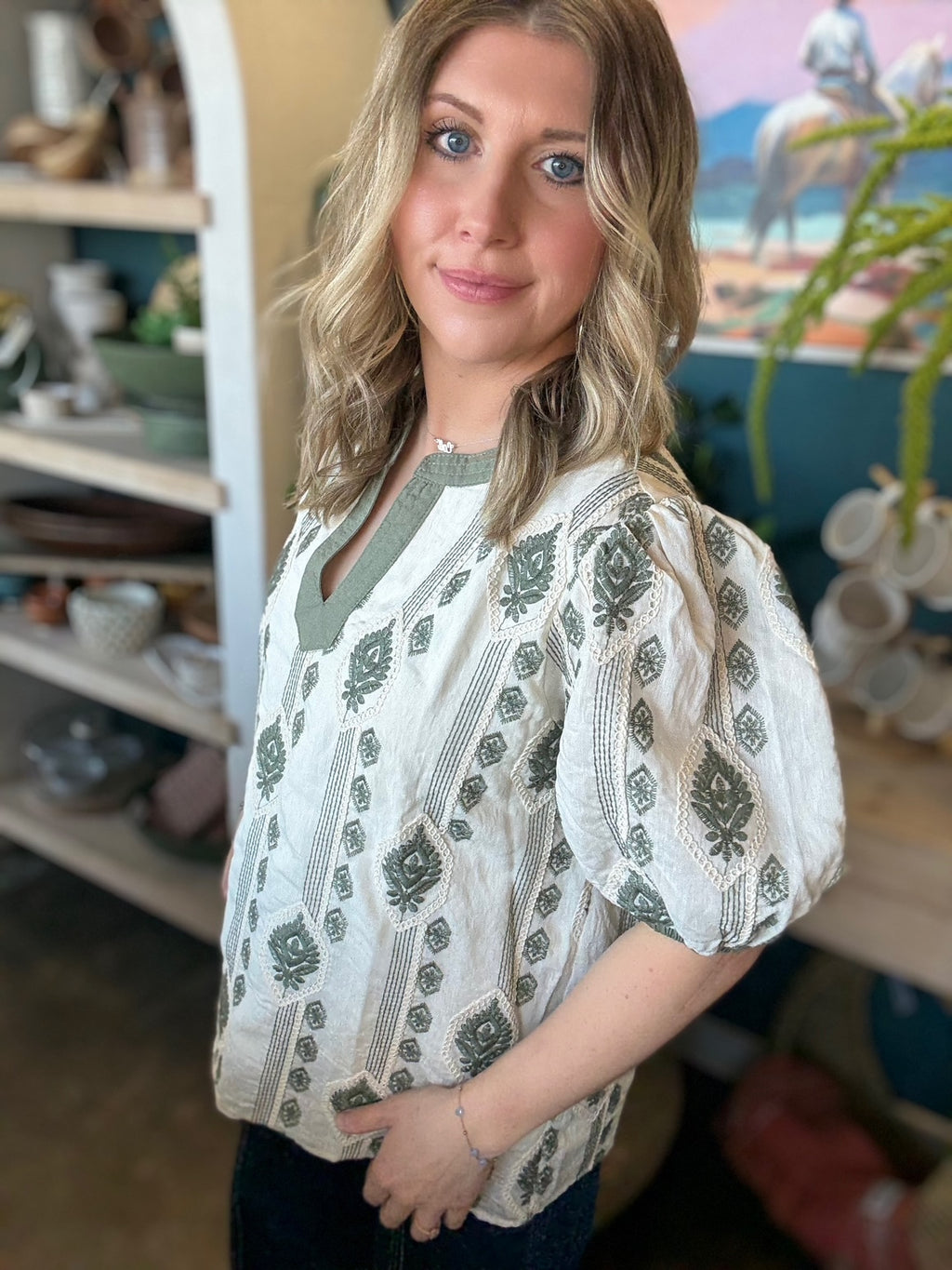 woman wearing ivory and olive printed puff sleeve boutique top with split neckline