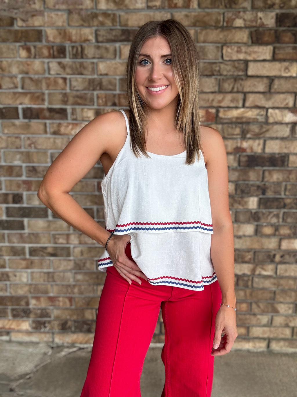 Woman wearing a white double layered woven linen cami top with red and navy ric rac trim