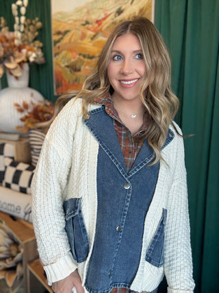 Woman wearing a cream open-knit twofer sweater with a washed-denim button front, flap pockets, and plaid collar accent.