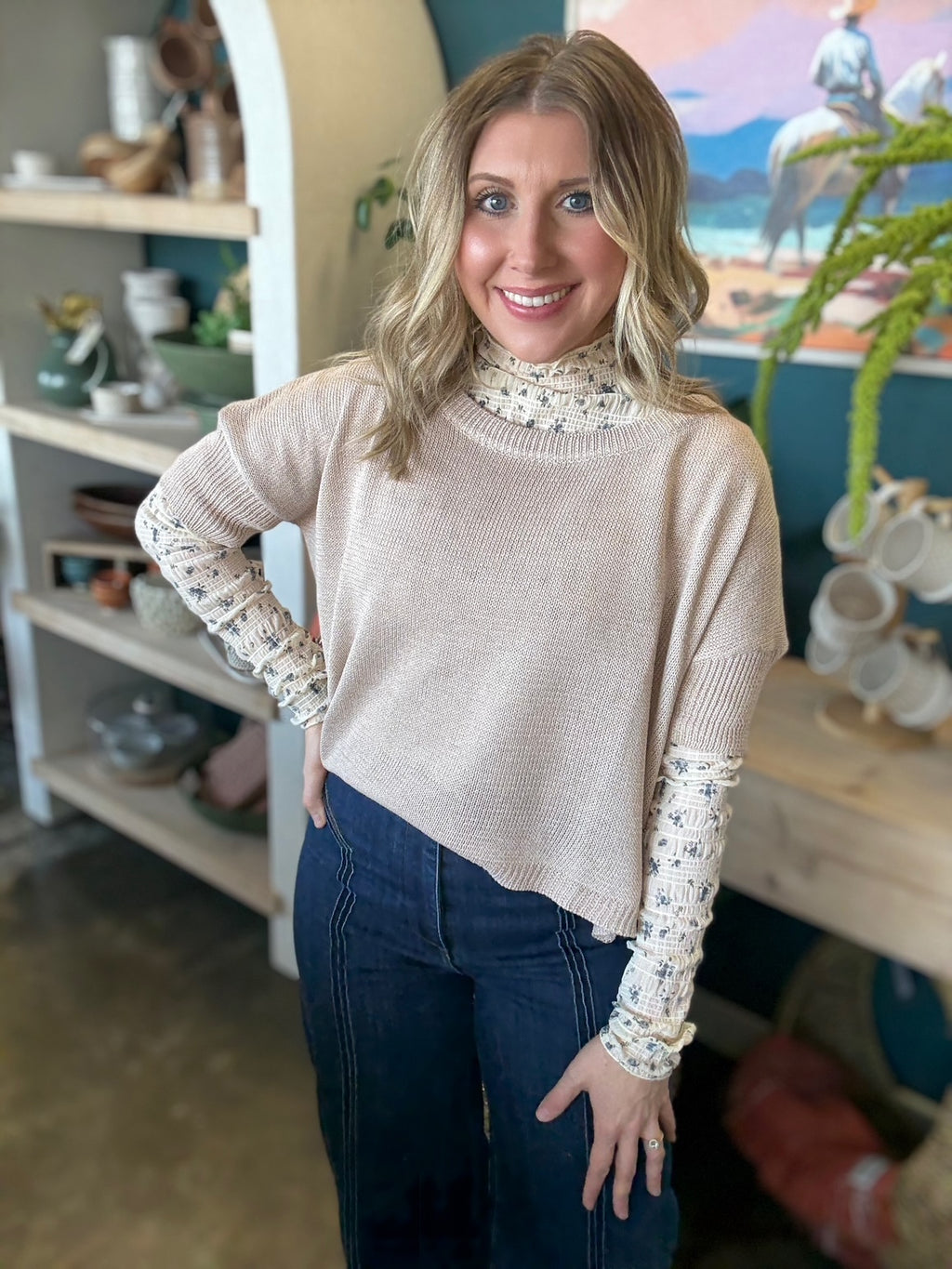 woman wearing oatmeal knit sweater layered over floral textured long sleeve top