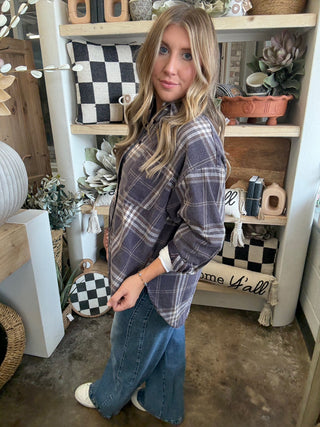 Woman wearing an oversized charcoal, taupe, cream, and brown plaid button-down shirt