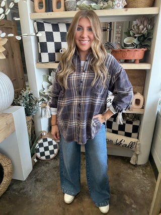 Woman wearing an oversized charcoal, taupe, cream, and brown plaid button-down shirt