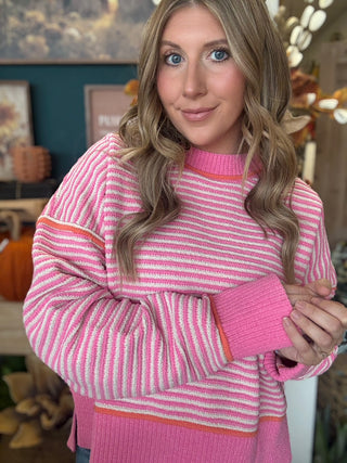 Woman wearing a pink-and-cream striped sweater with coral trim