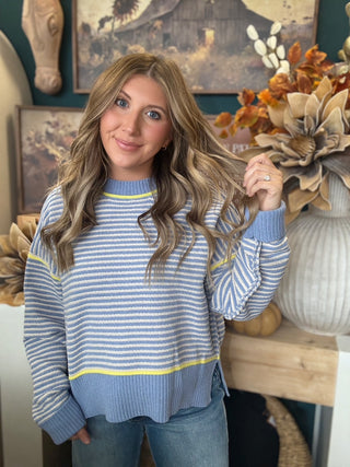 Woman wearing a dusty blue and cream striped sweater with yellow accents