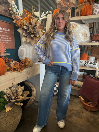 Woman wearing a dusty blue and cream striped sweater with yellow accents