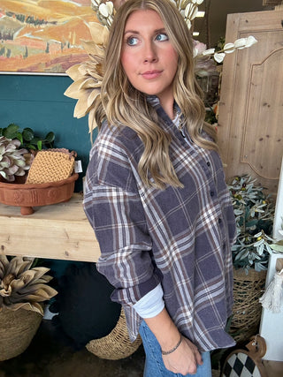 Woman wearing an oversized charcoal, taupe, cream, and brown plaid button-down shirt