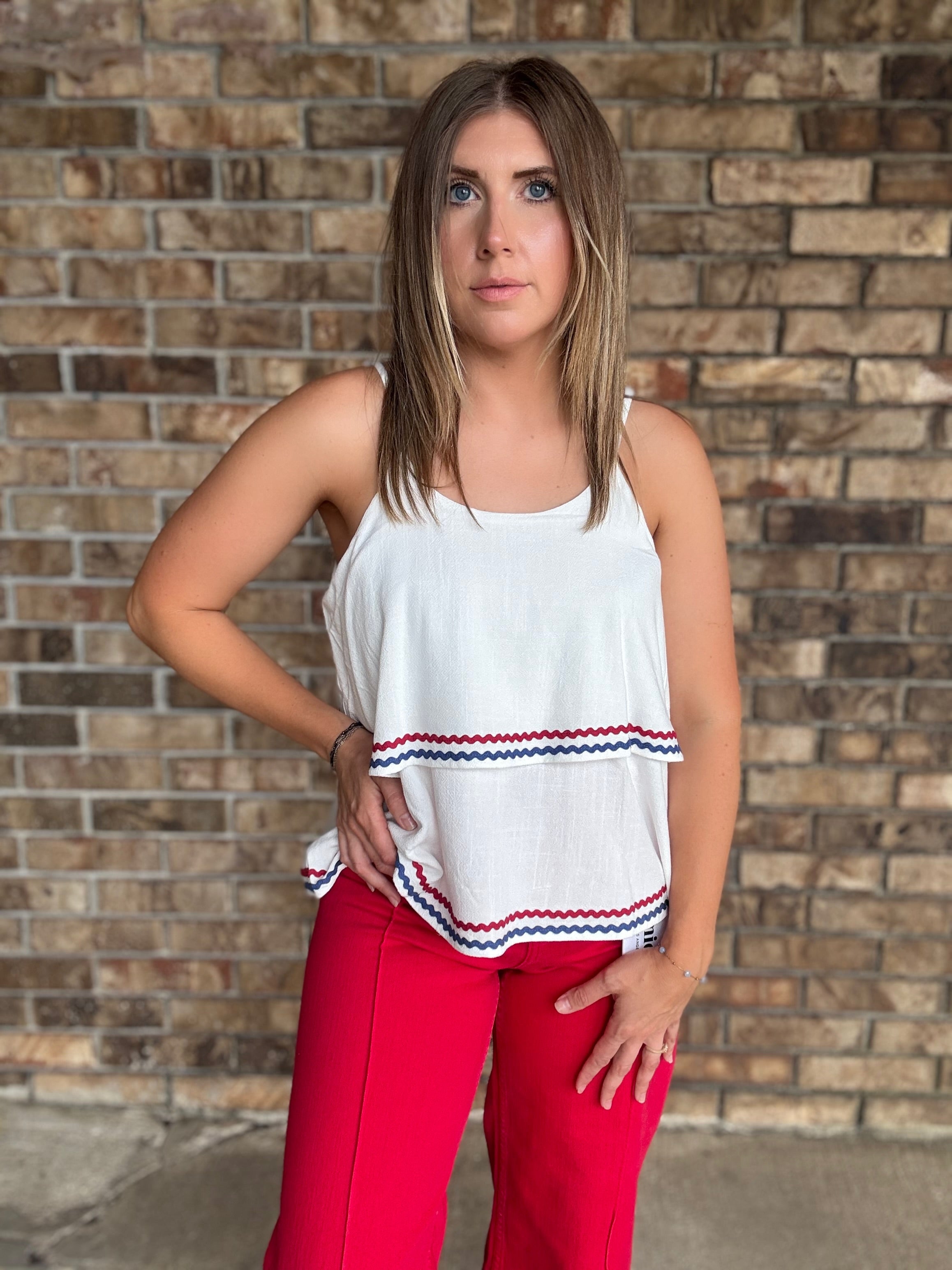 Woman wearing a white double layered woven linen cami top with red and navy ric rac trim